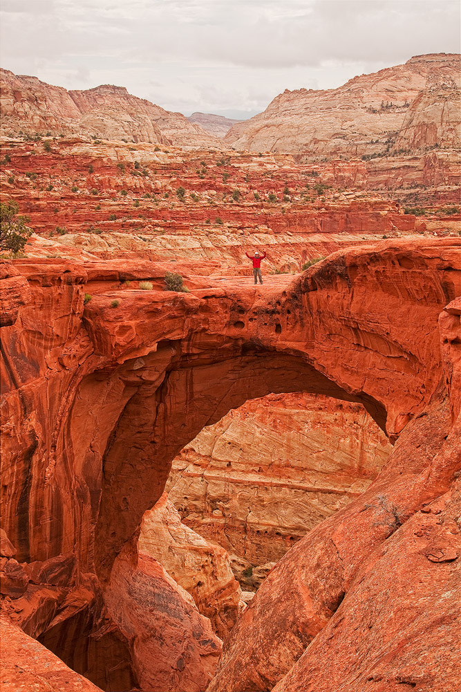 a hiker stands on cassidy arch, capitol reef national park, Utah
