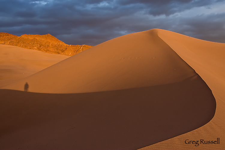 A hiker stands on Ibex Dunes at sunset, Death Valley National Park, California