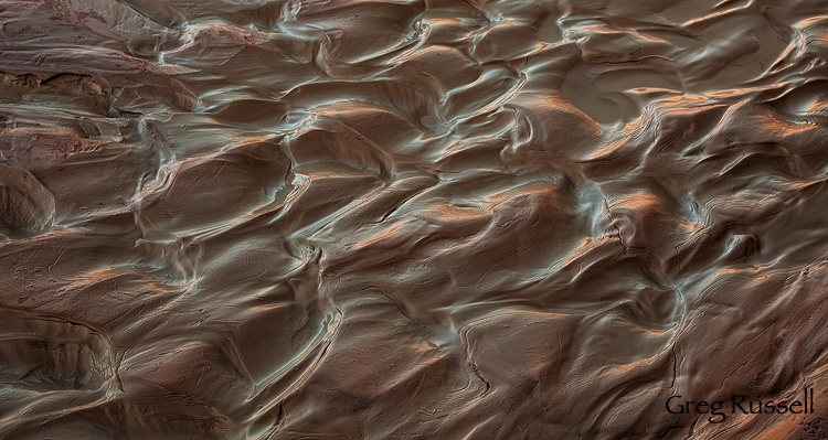 Wet clay mud reflects morning light from sandstone walls, Paria River in southern Utah