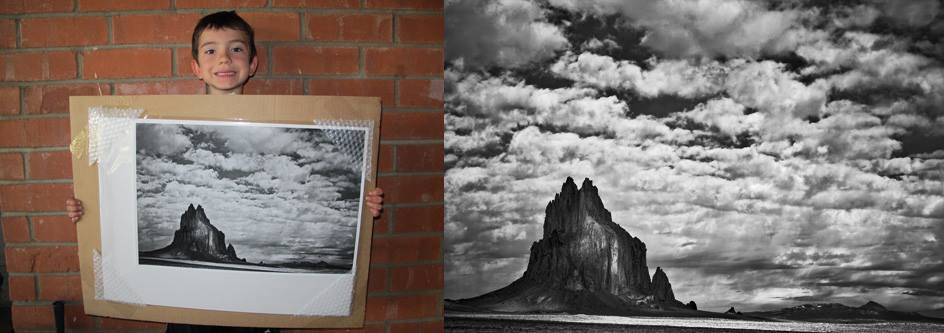 photo of a child holding a black and white print while standing against a brick wall